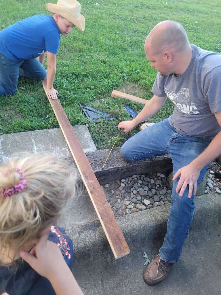 photo of a father and his son and daughter measuring wood for a shelf